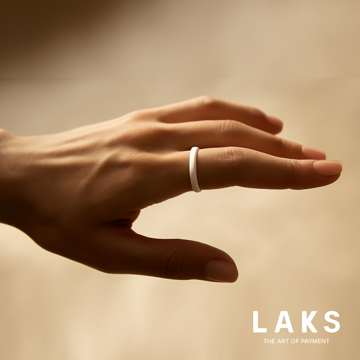 hand mit weißem Bezahlring am Zeigefinger auf beigen Hintergrund und Schriftzug Laks unten rechts