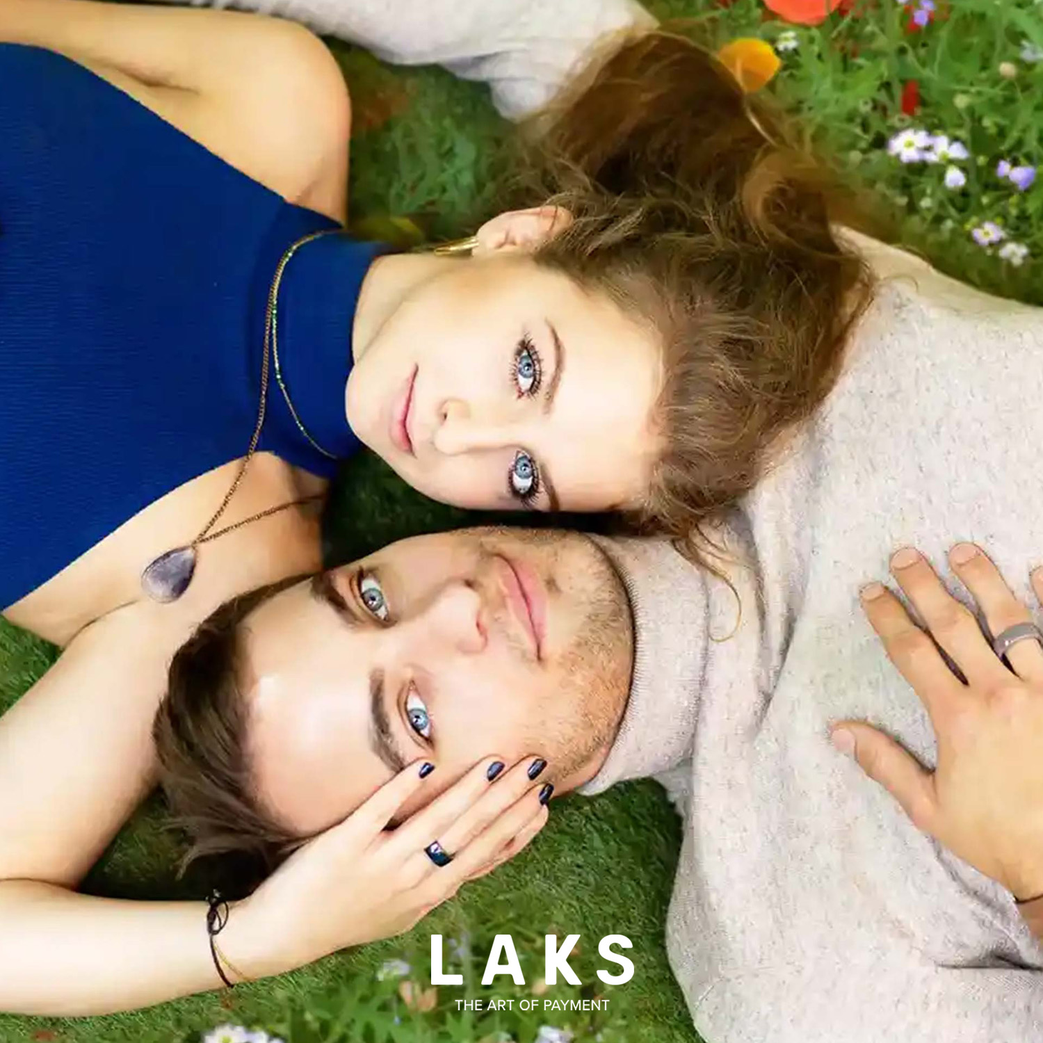 paar liegt sich gegenüber im gras und zeigen ihre Hände mit dem bezahlring am Finger