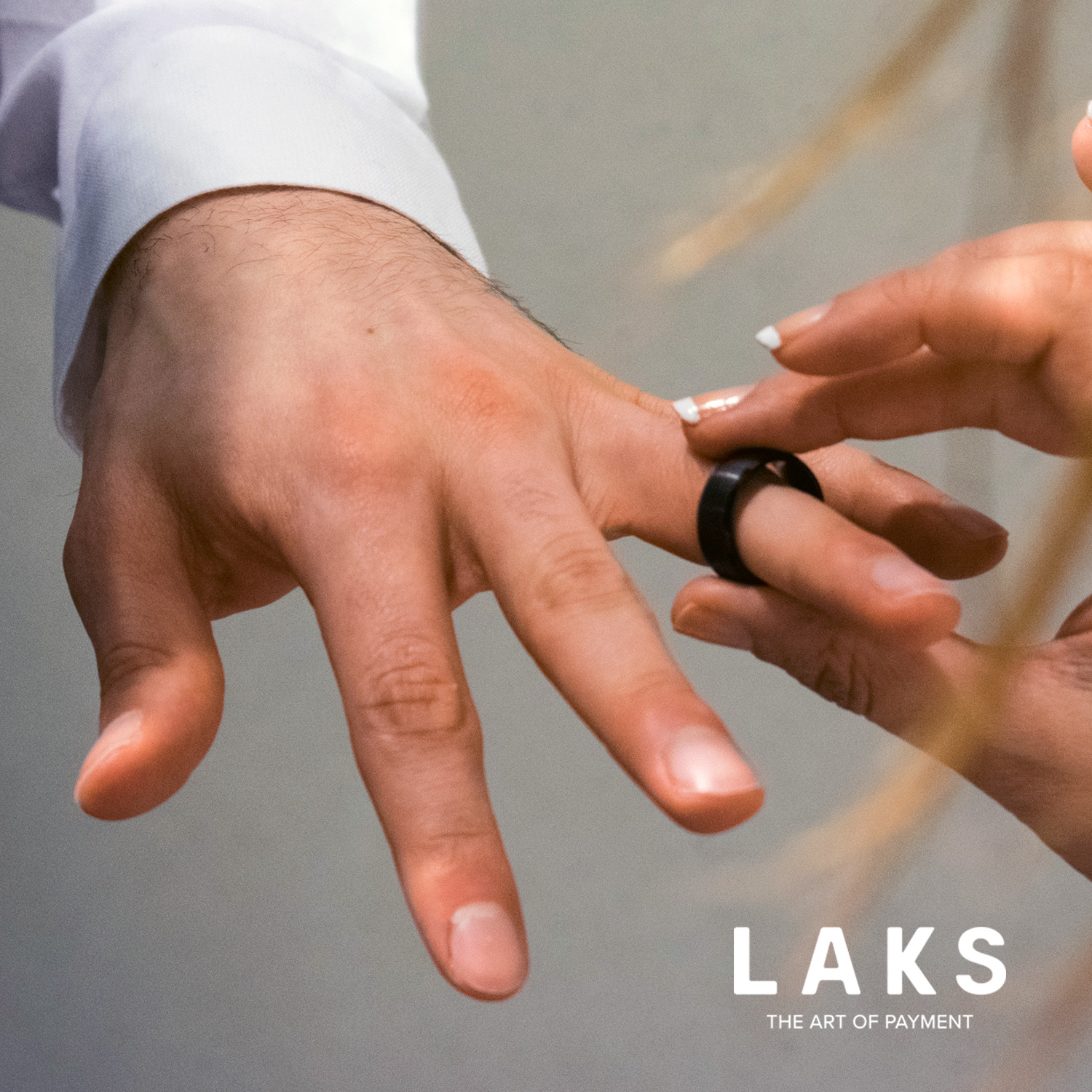 Frau steckt Mann einen schwarzen bezahlring an den Ringfinder und Schriftzug LAKS